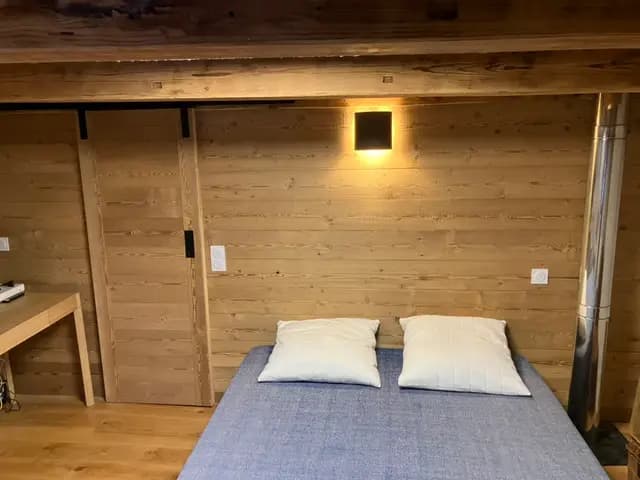 Lit double sous applique, mur lambrissé et porte coulissante