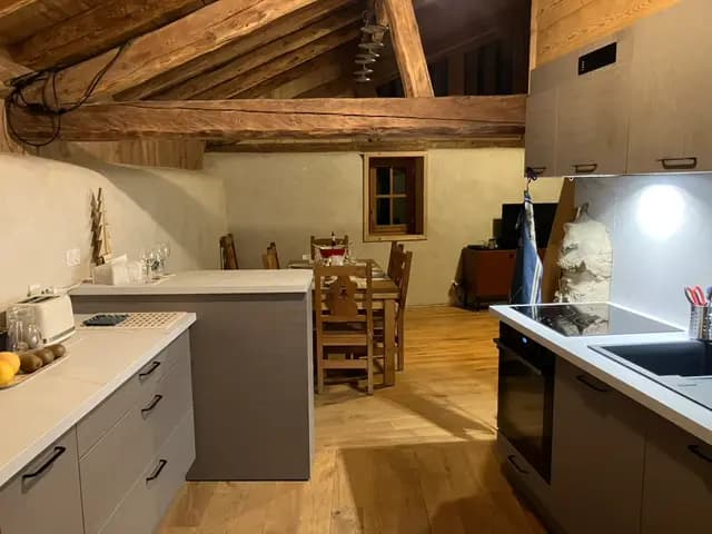 La cuisine sous les combles avec îlot et coin repas