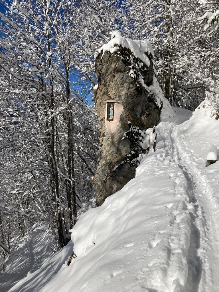 Oratoire au bord d'un sentier enneigé et ensoleillé